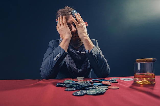 Foto ein wohlhabender reifer mann, der brandy trinkt und mit der aufregung in einem casino poker spielt