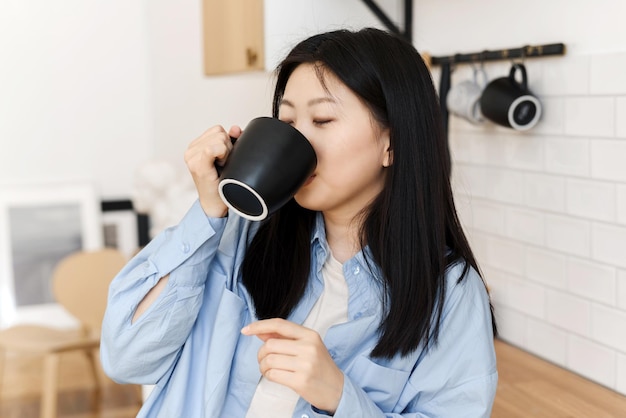 Foto eine charmante koreanerin in der küche mit einer tasse kaffee oder tee