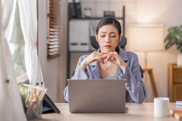 Foto eine glückliche junge asiatische frau benutzt einen laptop, während sie zu hause mit dokumenten arbeitet online-dokumentationsrechner, um die zahlen zu berechnen finanz-buchhaltungsbüro-konzept