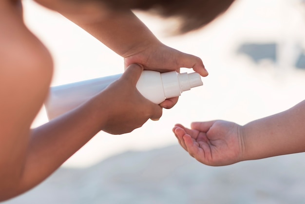 Eltern, die Sonnencreme in der Hand des Kindes anwenden