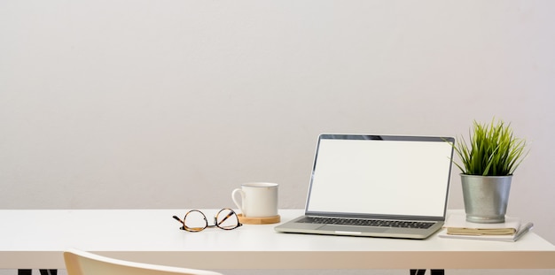 Escritório em casa simples com computador portátil de tela em branco aberta