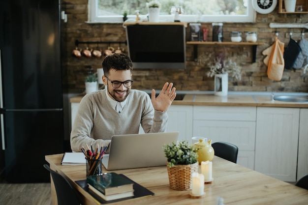 Feliz empresário tendo reunião online enquanto trabalhava no laptop em casa