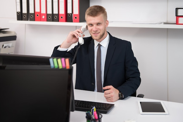 Feliz jovem empresário trabalhar no escritório moderno no computador