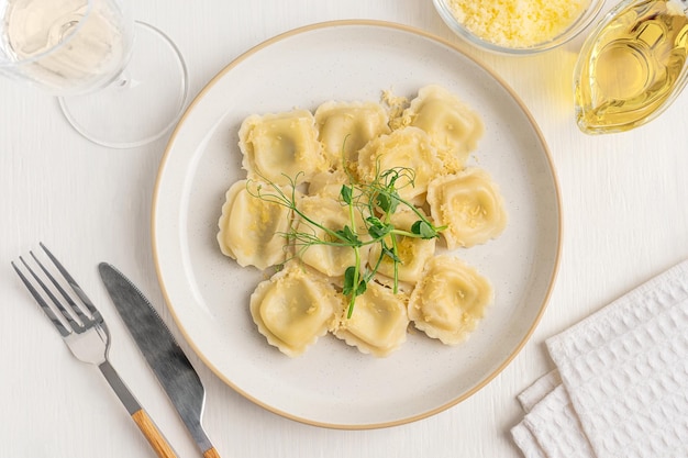 Foto flat lay com prato de pasta de ravioli caseiro italiano cheio de queijo servido com vinho branco