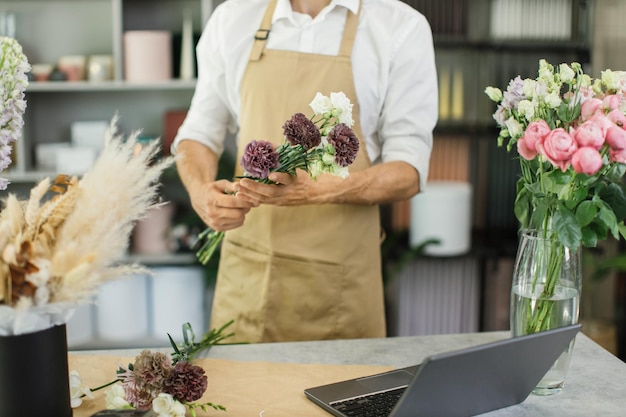 Foto florista coleta flores enquanto faz um lindo buquê de primavera de eustoma e cravo na loja