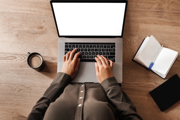 Frau arbeitet am Laptop mit weißem Bildschirm auf dem Boden sitzend, Ansicht von oben