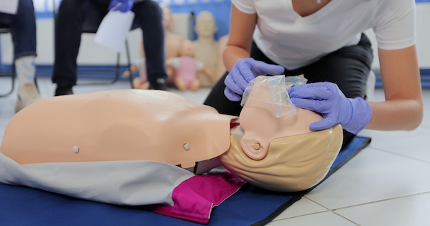 Frau, die CPR auf Schaufensterpuppe im Erste-Hilfe-Kurs praktiziert.