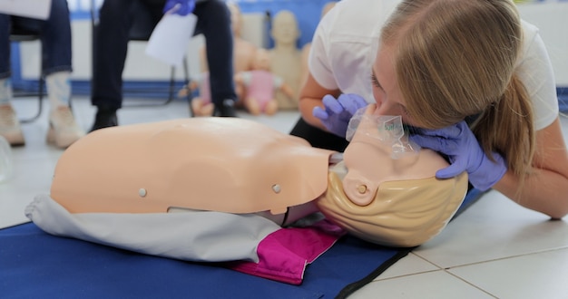 Frau, die CPR auf Schaufensterpuppe im Erste-Hilfe-Kurs praktiziert.