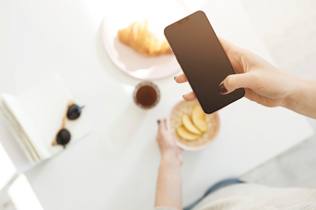 Frau, die ein Telefon benutzt, um ein Foto von ihrer Mahlzeit zu machen