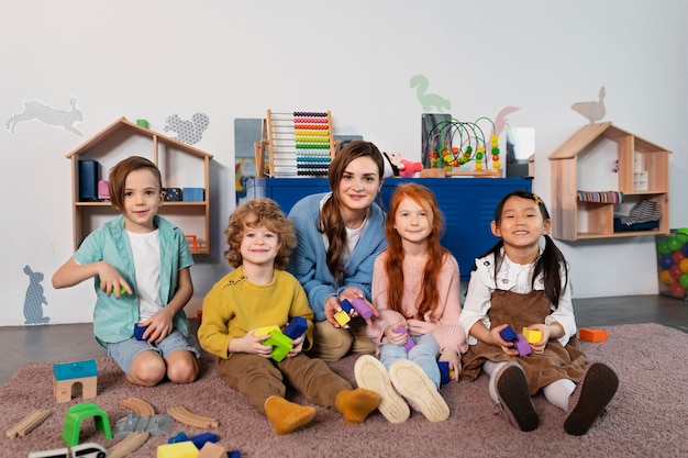 Full-Shot-Smiley-Lehrer und Kinder posieren zusammen