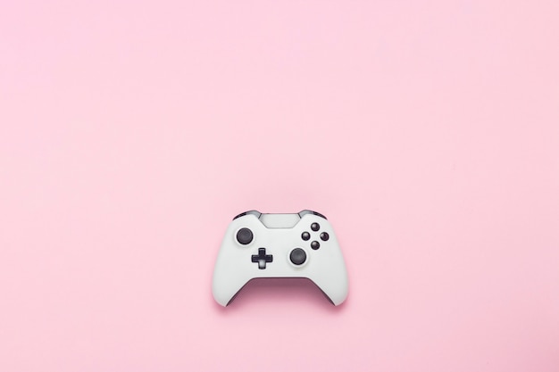 Gamepad branco sobre um fundo rosa. Jogo de conceito no console, jogos de computador. Vista plana leiga, superior.