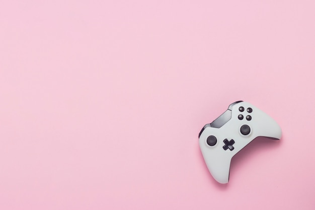 Gamepad branco sobre um fundo rosa. Jogo de conceito no console, jogos de computador. Vista plana leiga, superior.