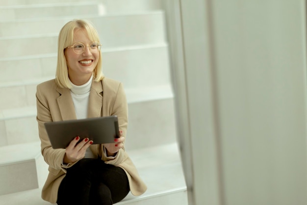 Geschäftsfrau mit digitalem Tablet auf modernen Bürotreppen