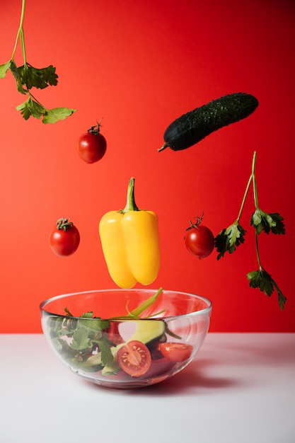 Gesunder Salat mit fliegenden Gemüsezutaten auf Rot