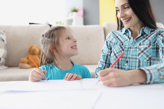 Glückliche Mutter und Tochter zeichnen mit Bleistiften auf Papier