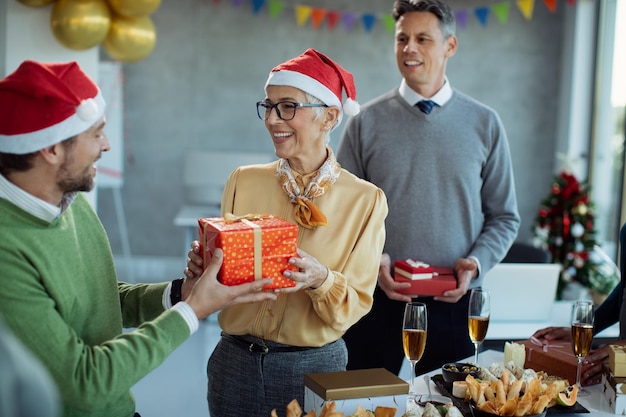 Glückliche reife Geschäftsfrau, die Weihnachtsgeschenk auf Büroparty erhält