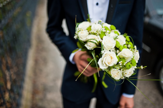 Groomsman segurar na mão dois buquês para damas de honra