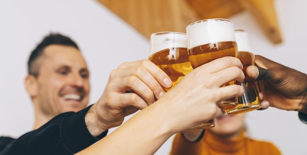 Foto gruppe von freunden, die biergläser im englischen pub der brauerei genießen junge leute jubeln im bar-restaurant freundschafts- und jugendkonzept