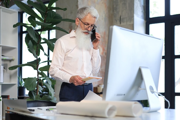 Gut aussehender, reifer Architekt, der etwas zeichnet, während er im Büro arbeitet