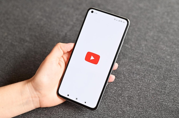 Hand, die ein brandneues Mobiltelefon hält, das die Youtube-App auf dem Touchscreen anzeigt