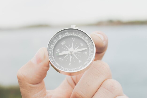 Foto hand hält einen kompass vor dem meer konzept des abenteuers reisen selektive fokus person süd