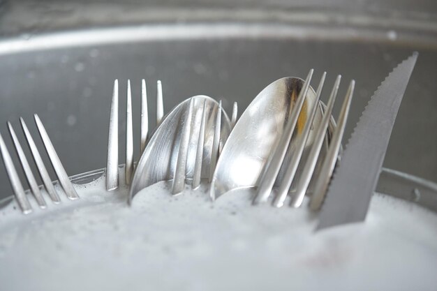 Foto hausarbeit, abwasch und haushaltskonzept - nahaufnahme von schmutzigem geschirr, das in der küchenspüle gewaschen wird