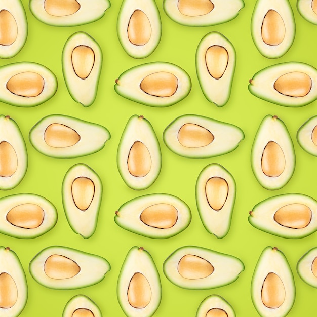 Hintergrund von reifen Avocadohälften auf hellgrünem Hintergrund.