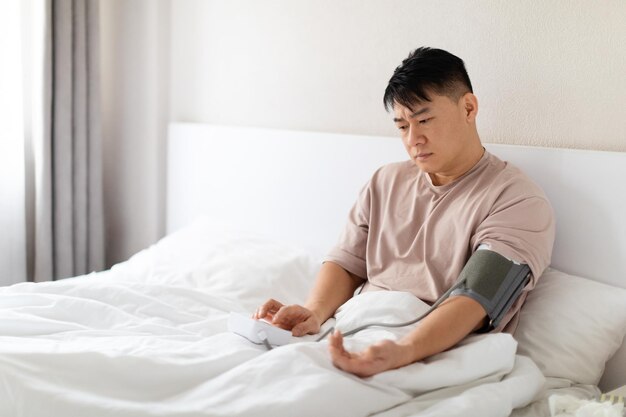 Foto homem asiático preocupado fazendo check-up matinal depois de acordar