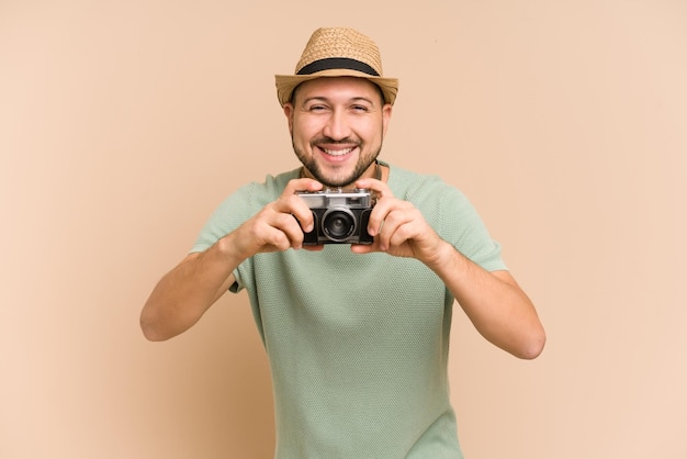 Homem latino adulto segurando e usando uma câmera vintage isolada