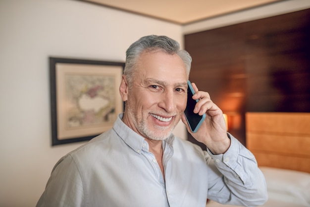 Homem sorridente. Empresário de meia-idade sorridente falando ao telefone e parecendo satisfeito