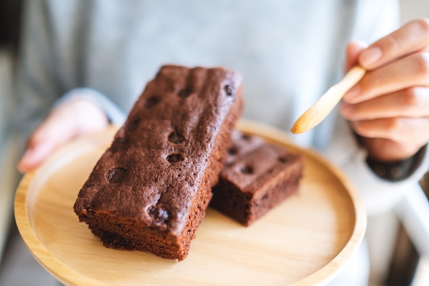 Foto imagem de close de uma mulher comendo um delicioso bolo de brownie com uma colher