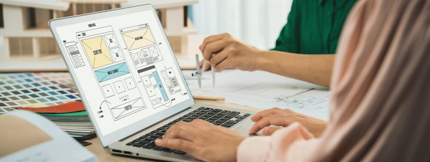 Foto imagem recortada da equipe de designers de interiores discutindo a cor do material enquanto o laptop exibe designs de wireframe para celulares aplicativo e site design criativo e conceito de negócios variado