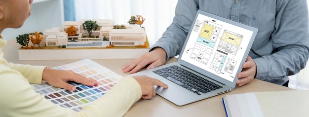 Foto imagem recortada de designer de interiores apresenta cores a partir de amostras de cores enquanto o laptop exibe designs de wireframe de site para celulares aplicativo e site design criativo e conceito de negócios variado