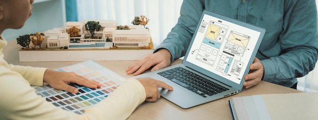 Foto imagem recortada de designer de interiores apresenta cores a partir de amostras de cores enquanto o laptop exibe designs de wireframe para dispositivos móveis aplicativo e site design criativo e conceito de negócios variado