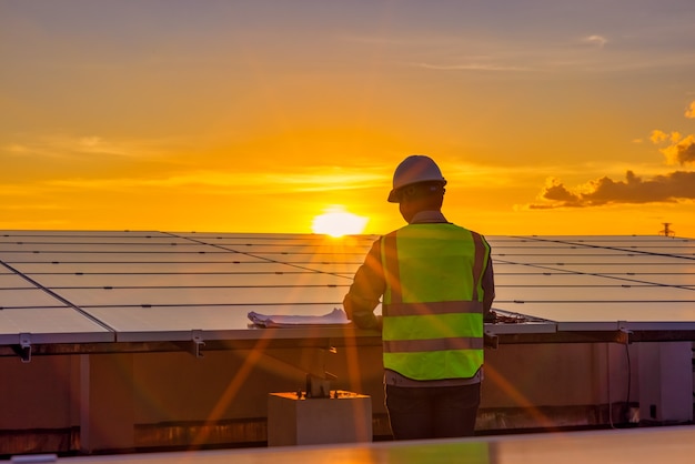 Ingenieur mit Laptop an Sonnenkollektoren auf dem Dach bei Sonnenuntergang Himmel Ingenieur arbeitet an einer Photovoltaik