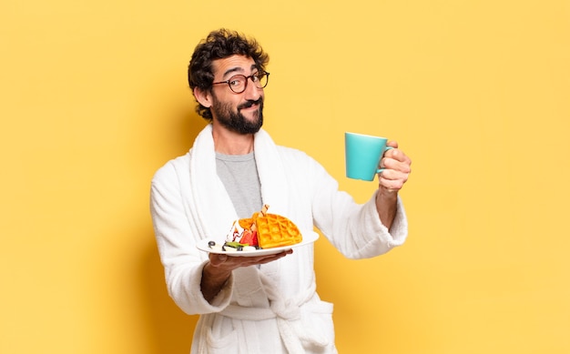 Jovem barbudo vestindo roupão de banho e tomando café da manhã