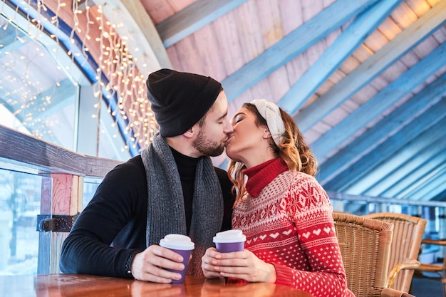 Jovem casal atraente em um encontro no café, conversando e beijando na época do Natal