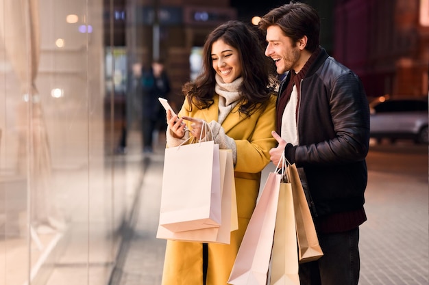 Foto jovem casal com smartphone perto de shopping