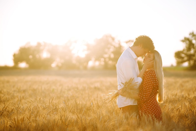 Jovem casal feliz abraçando em um campo de trigo no pôr do sol aproveitando o tempo juntos