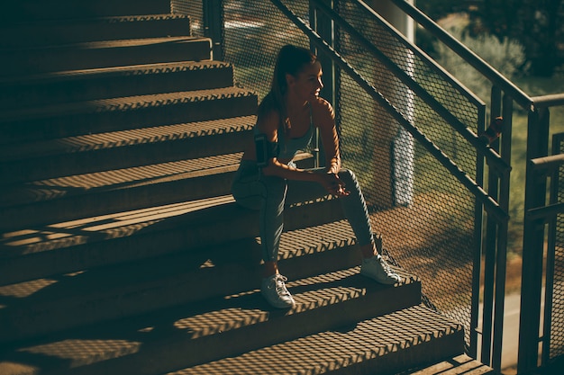 Jovem corredor feminino descansando nas escadas