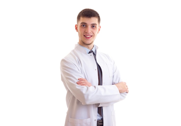 Jovem feliz com cabelo castanho na camisa azul, gravata e vestido de médico em fundo branco em estúdio