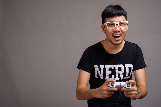 Foto jovem nerd asiático usando óculos contra o cinza