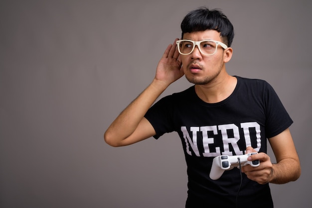 Foto jovem nerd asiático usando óculos contra o cinza