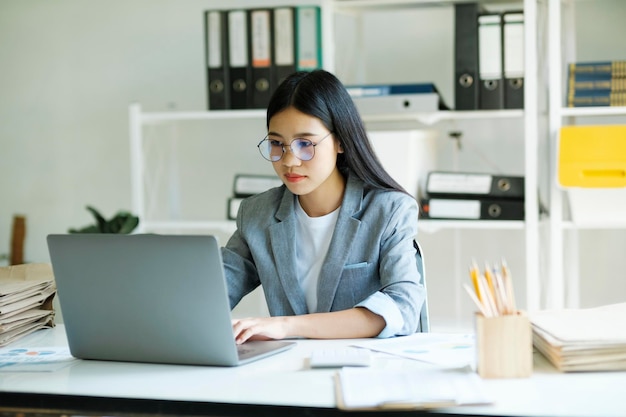 Junge asiatische Geschäftsfrau oder Studentin, die online am Computer-Laptop arbeitet