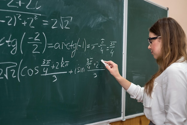 Junge College-Student schreiben mathematische Übung an der Tafel während einer Klasse. Ausbildung