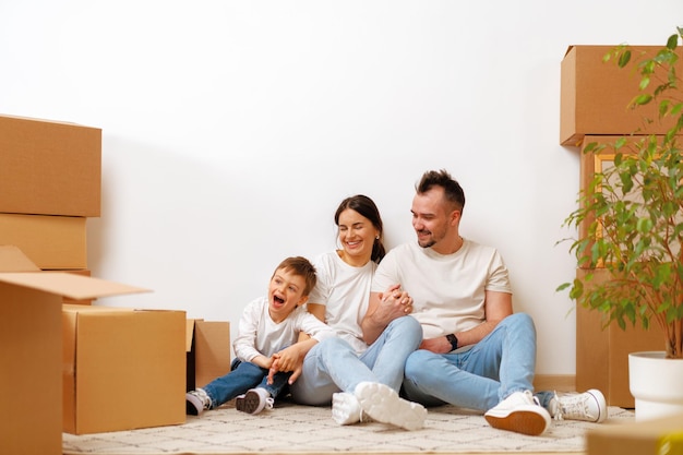 Junge Eltern und Sohn amüsieren sich während des Umzugstages in ein neues Haus