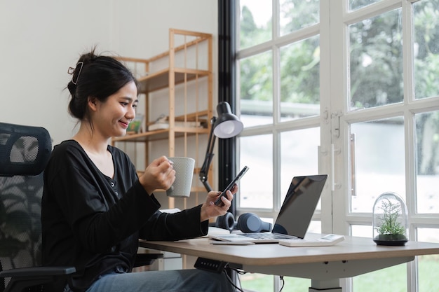 Foto junge frau studiert zu hause online mit laptop und smartphone in einem modernen home-office mit natürlichem licht