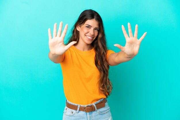 Junge kaukasische Frau auf blauem Hintergrund isoliert, die mit den Fingern zehn zählt