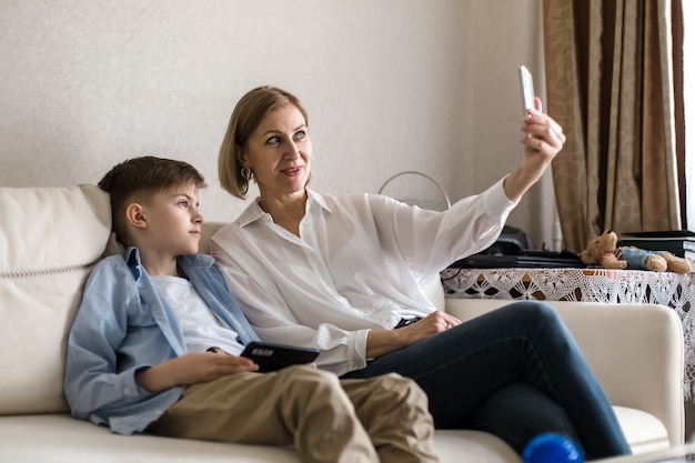 Junge und erwachsene Frau machen ein Selfie am Telefon, während sie auf der Couch sitzen