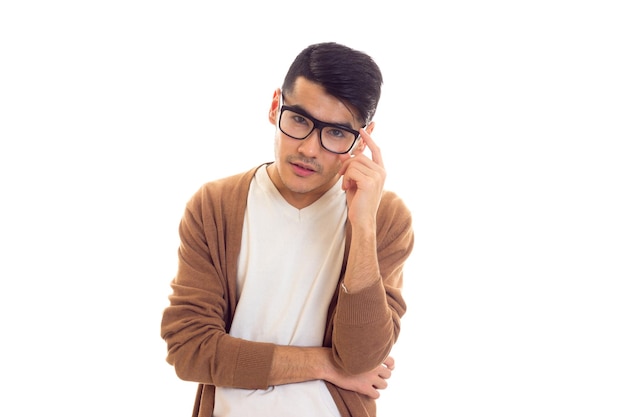 Junger, elegant aussehender Mann mit schwarzen Haaren in weißem T-Shirt, brauner Strickjacke mit schwarzer Brille